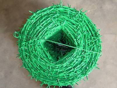A roll green PVC coated barbed wire on the ground.