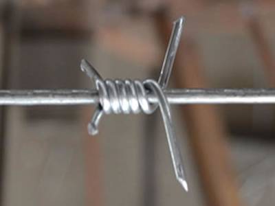 A single strand barbed wire on the gray background.