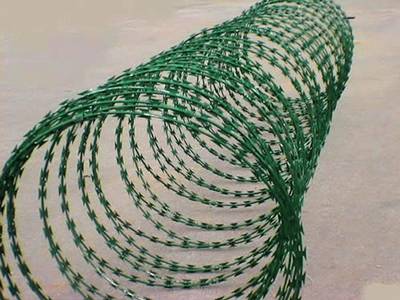 A roll of green color PVC coating concertina razor wire on the ground.