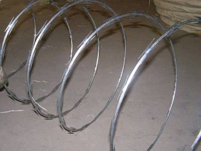 A roll of single spiral concertina razor wires on the ground.