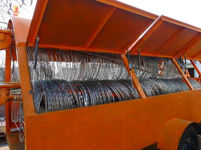 An orange tailor deployment with three rolls of concertina razor wire on the ground.