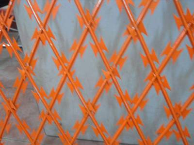 An orange color straight razor wire lying on the wall.