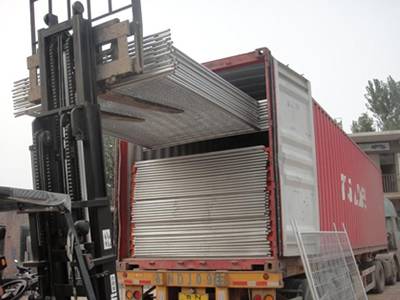 A forklift is transporting welded wire mesh fences into container.