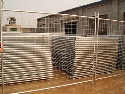 Two pieces of welded wire temporary fences in the yard with several stacks of welded wire mesh panels.