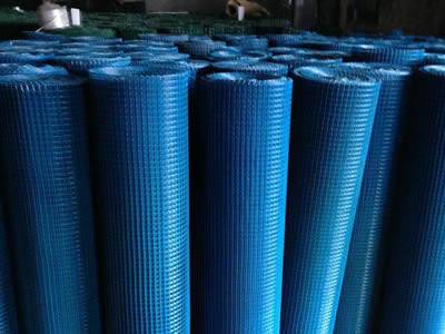 Several rolls of blue welded wire rolls on the ground.