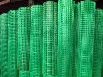 Several rolls of grass green welded wire rolls on the ground.