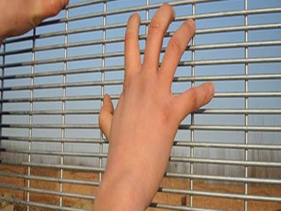 A pair of hands are putting on the galvanized anti-climb fence.