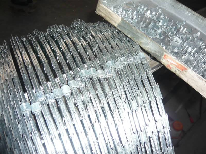 Galvanized razor concertina coils and clips in concertina wire workshop.