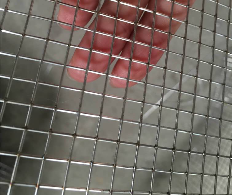 Square stainless steel welded wire mesh sheet on a hand.