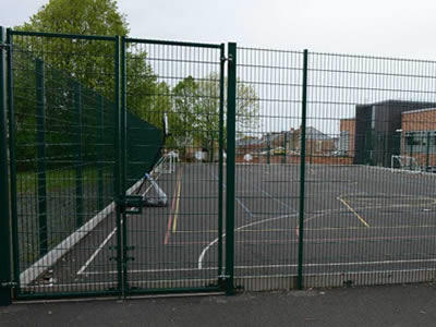 A green welded football fence with a gate is installed on the concrete ground beside the residence.