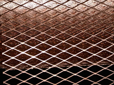 A roll of copper alloy expanded metal mesh on the gray background.