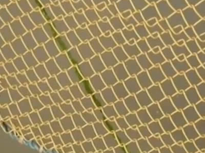 A piece of copper alloy chain link mesh on the gray background.