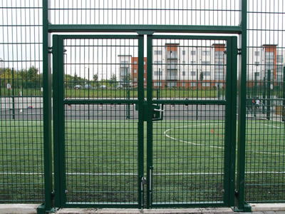 A green welded football field fence with a two-leaf gate is installed at a stadium.