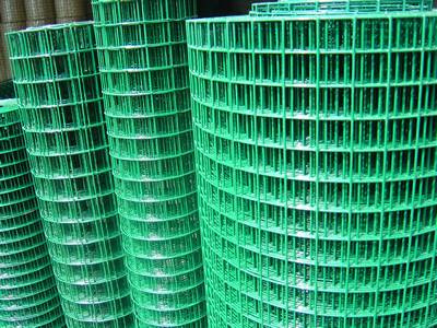 Four rolls of green PVC welded wire mesh in warehouse