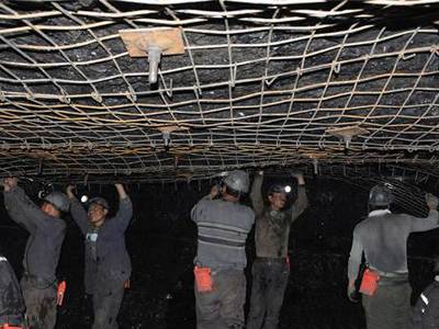 Several workers are installing the woven wire mesh onto tunnel roof.