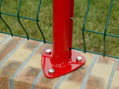 A red color peach post is bolted down onto the brick ground.