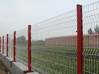 White 3D security fence panels and red peach posts are installed in the farmland.