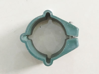 A green color plastic clamp on the ground.