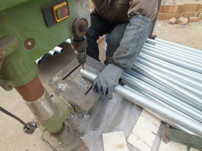 A worker is drilling holes on the steel pipe.