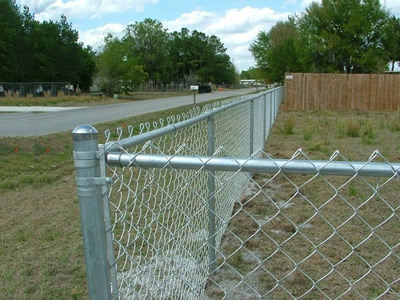 Two pieces of chain link fences are connected by the round post with metal fence post cap.