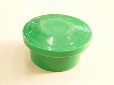 A green color plastic fence post cap on the ground.