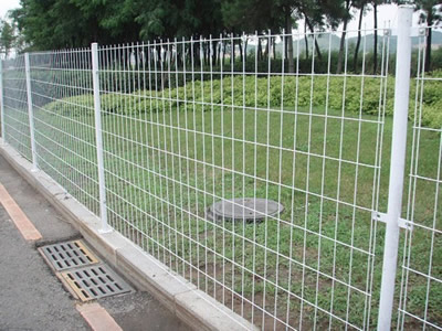 Several double edge fences with straight round post besides of the road.