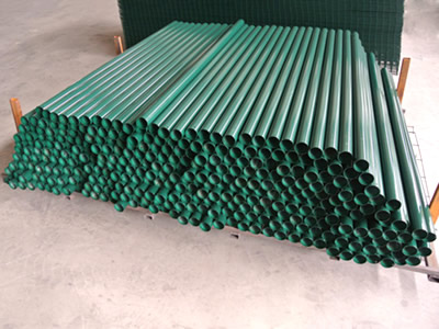 Several green color PVC coated round posts on the ground.