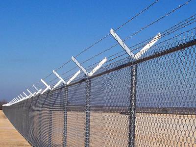 Chain link fences are connected by the round post with two-arm extensions for barbed wire.