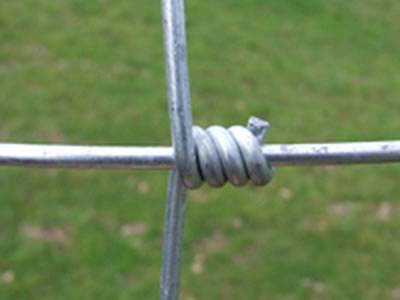 A detail of hinge joint of woven wire cattle fence.