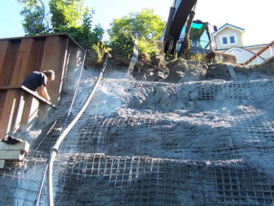A person is repairing cabin besides the shotcrete slope.