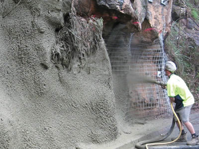A worker is spraying pipe the welded wire mesh installed mountain