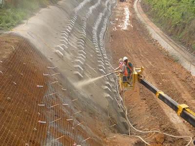Half of the slope has finished the first shotcrete yet, another half of the slop is sprayed with concrete.