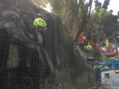 laborers are fixing drain pipe and welded wire mesh on a small mountain.