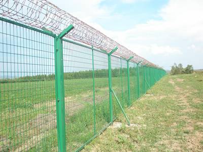 Green color framework metal fence are installed in the grassland with razor wire on the square post.