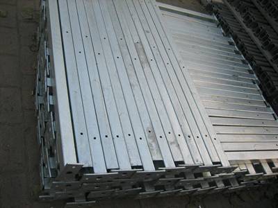 Several pieces of galvanized square post on the ground.