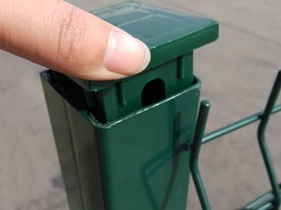 A hand is installing the plastic fence post cap onto the 3D security fence.