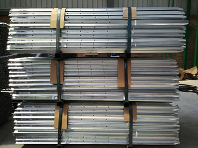 Three pallets of galvanized star pickets with consistent holes on the ground.