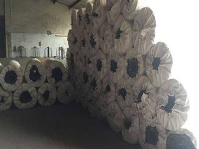 Several rolls of straight razor wire fences with woven bag package on the ground.