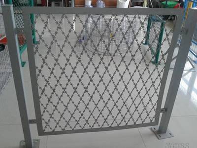 A piece of grey color straight razor wire fence is raised by the square posts.