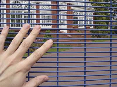 A hand is putting on the blue PVC coated anti-climb fence.