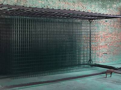Several pieces of welded wire mesh panels is hanging vertical on the shelf besides of the PVC coating pit.